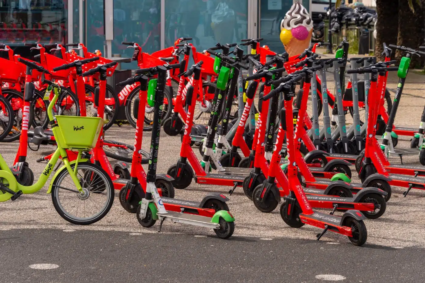 Uber Jump scooters and other scooters sit in front of a building