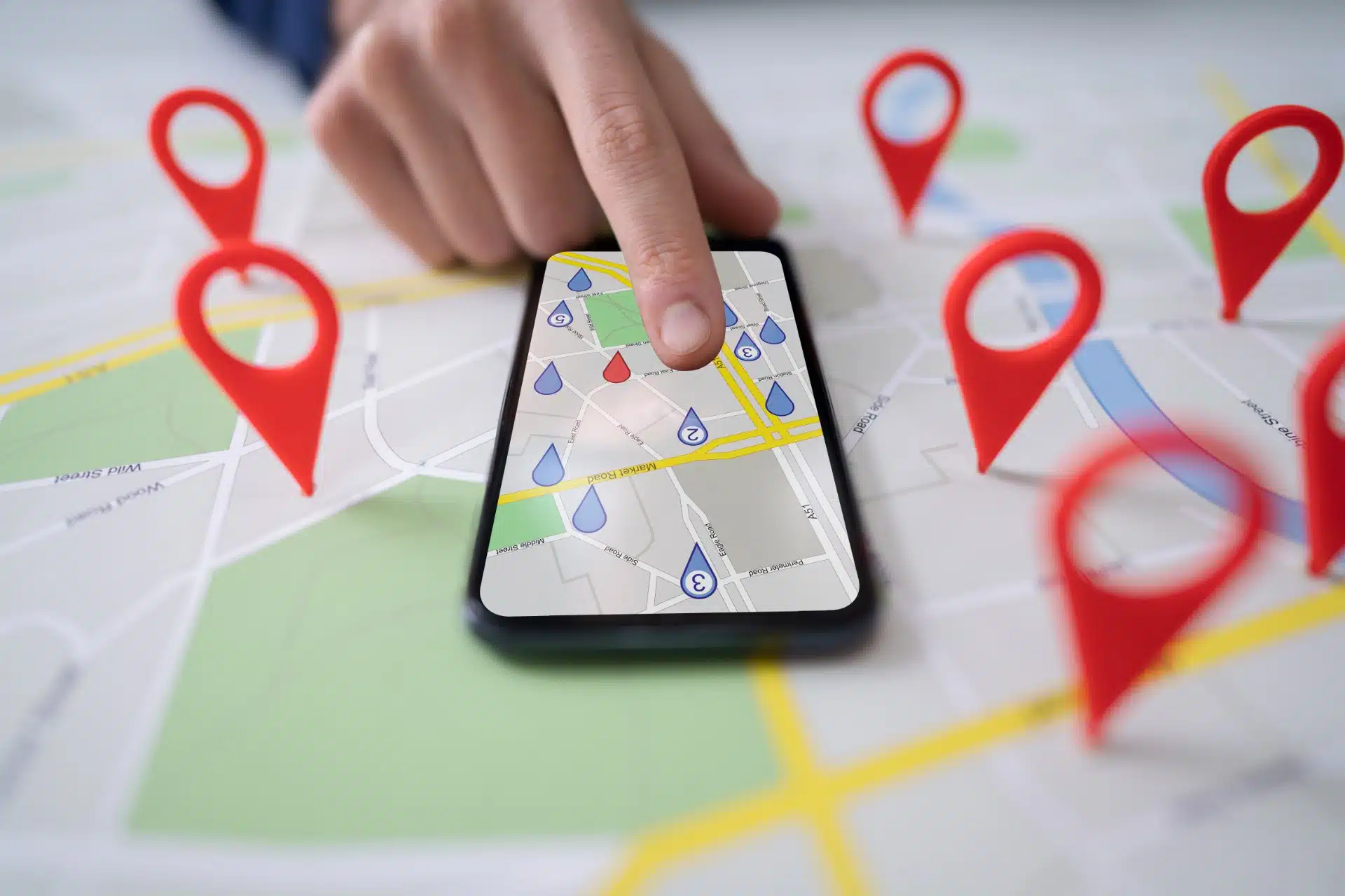 A person uses a map on a smartphone lying on top of a map showing red location markers - Google location tracking