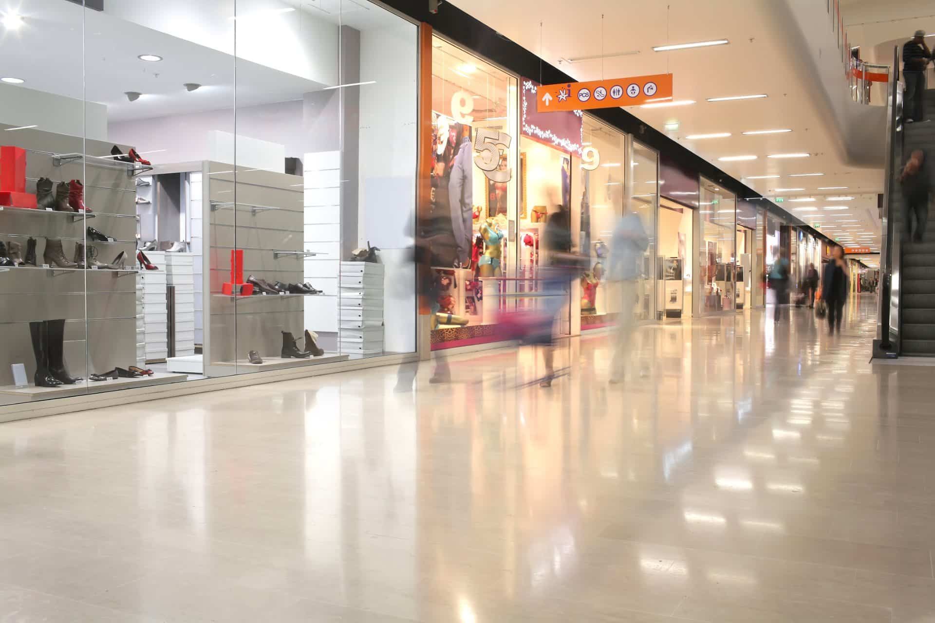 Interior of indoor shopping mall with blurry shoppers walking bya