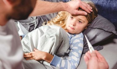 A man takes a sick young girl's temperature - Dollar General pain reliever