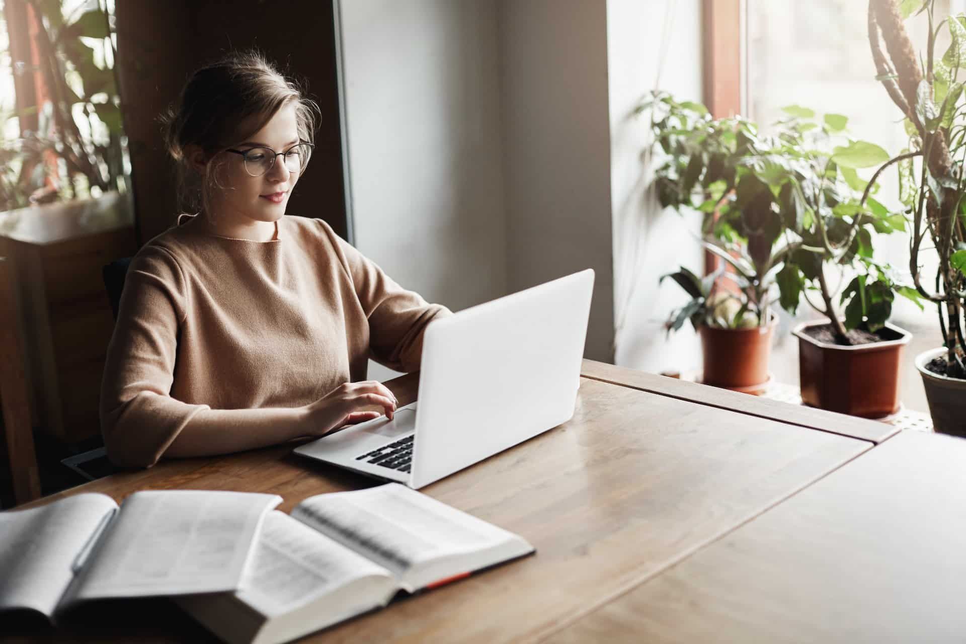 A female student works on a laptop with open books nearby - The word "Test!" is spelled out in red keys on a white keyboard - College Board AP Exams