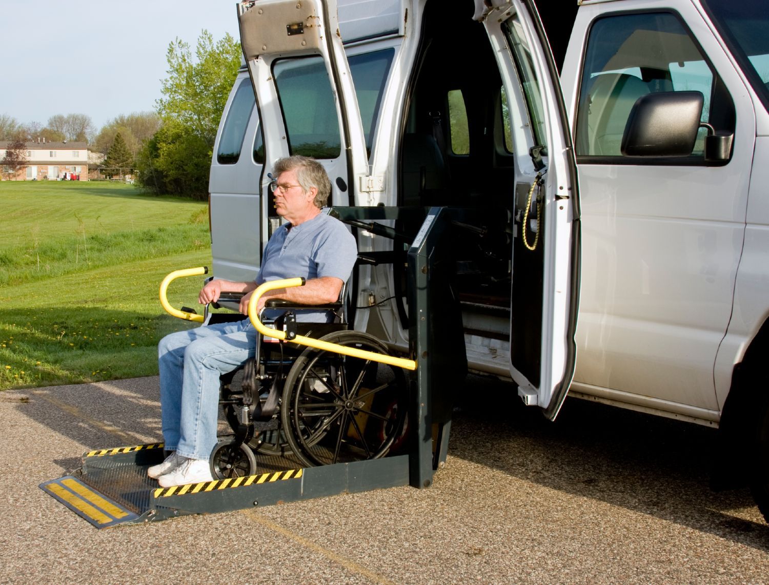 A man in a wheelchair sits on a lift on a white van - lyft app