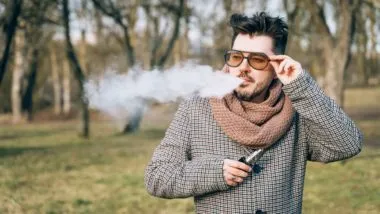 Bearded man in sunglasses vaping outdoors