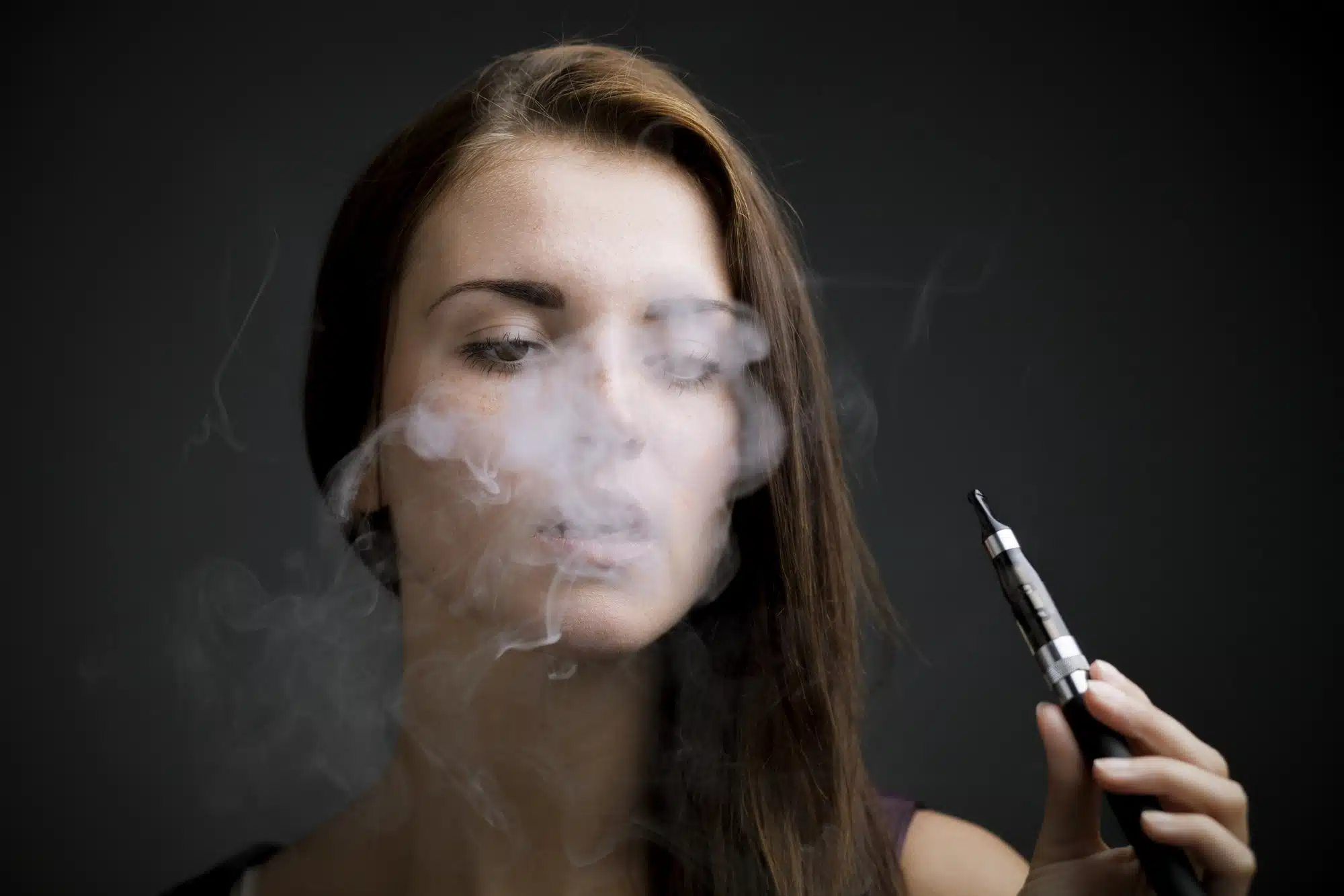 Woman with vaping pen surrounded by vaping cloud