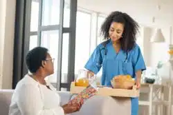 Nurse brings food tray to nursing home resident
