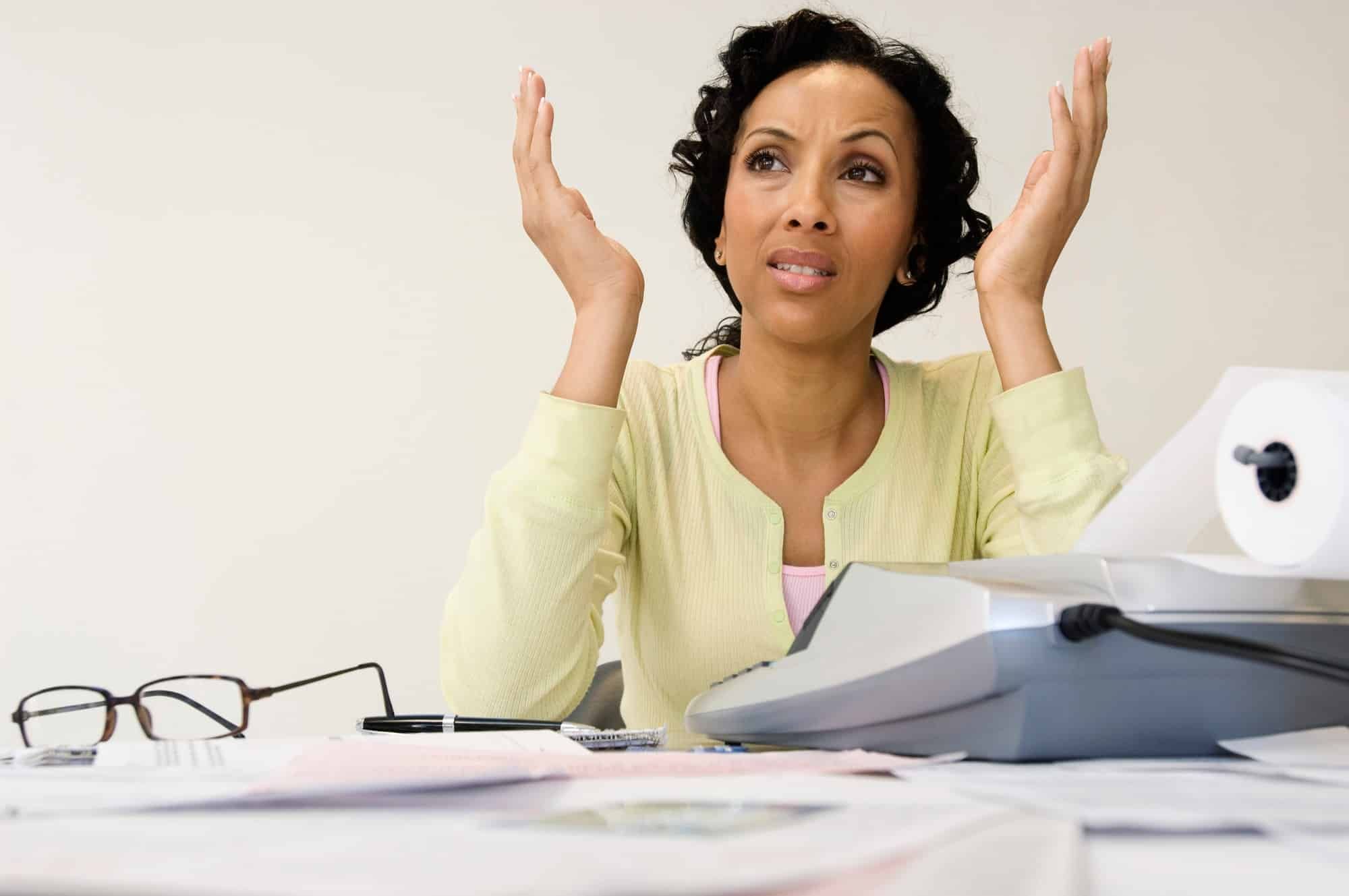 Unhappy businesswoman with calculator and expense reports