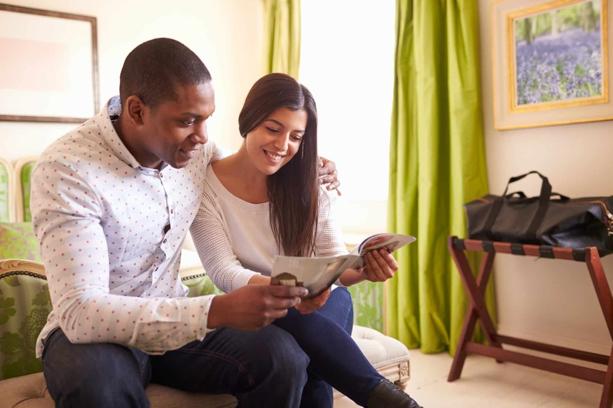 Young couple reading brochure in hotel room