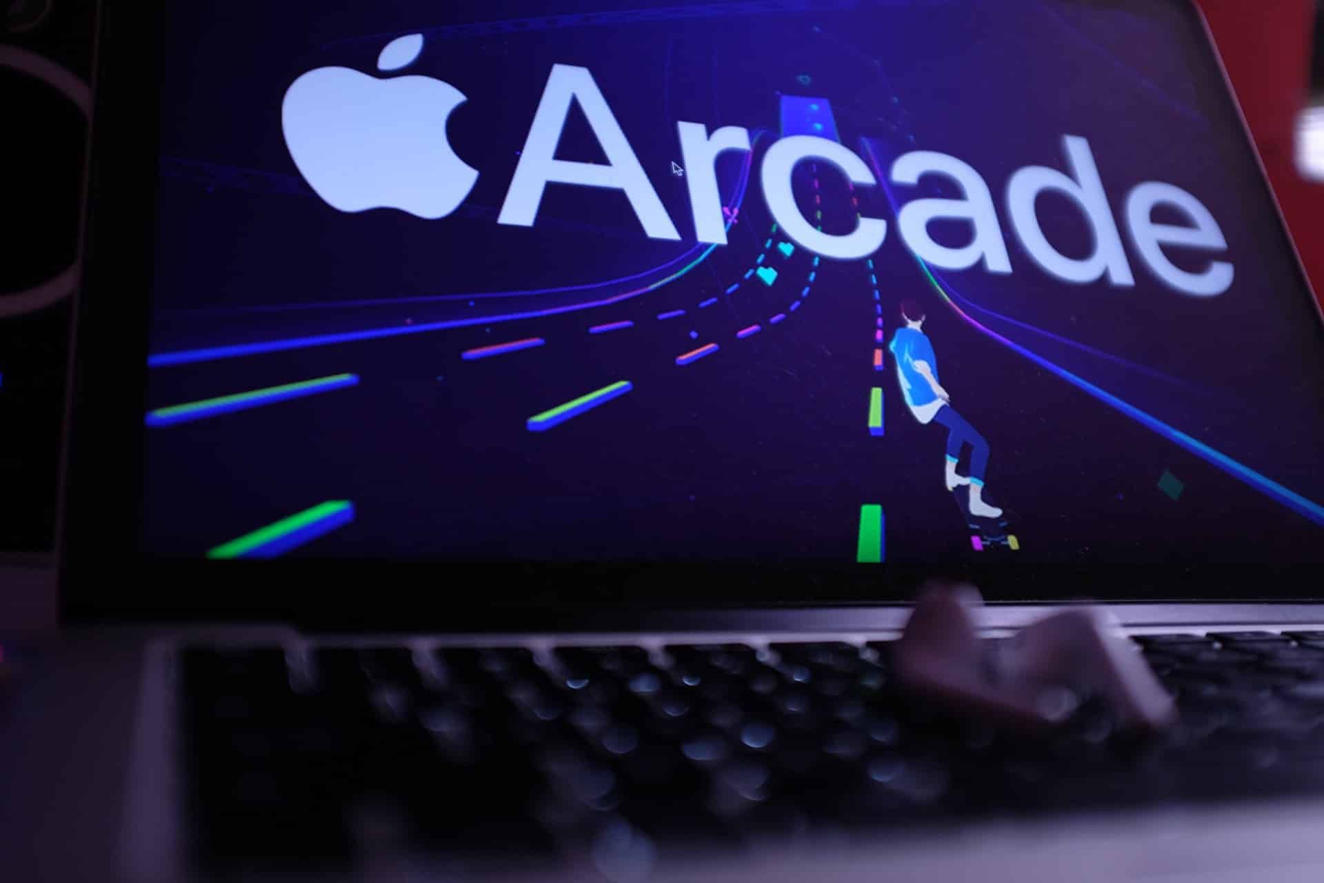 A MacBook Pro with Apple Arcade on the screen and AirPods lying on the keyboard