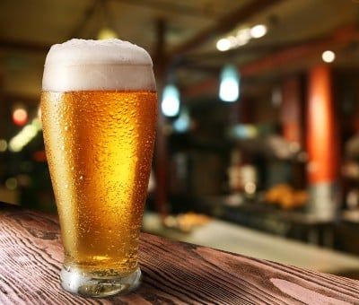 A glass of beer sits on a bar - Olympia beer