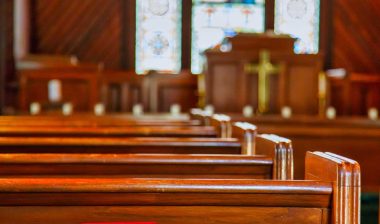 Empty wooden pews in a church with a stained glass window - colorado churches