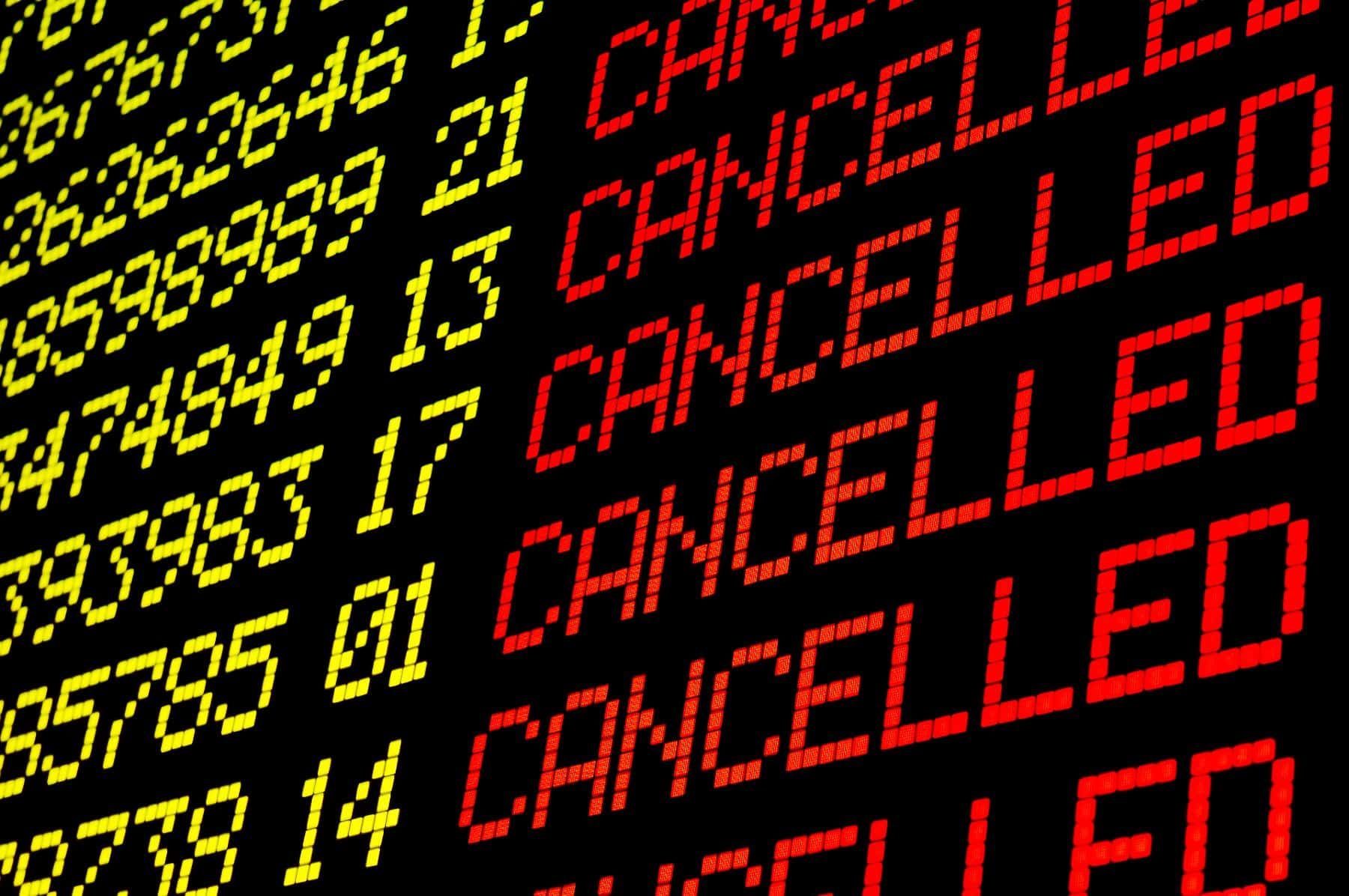 A airport flight status board shows several canceled flights - refund policy