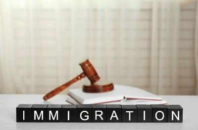 Black letter blocks with white letters that read "immigration" sit in front of a gavel - uscis