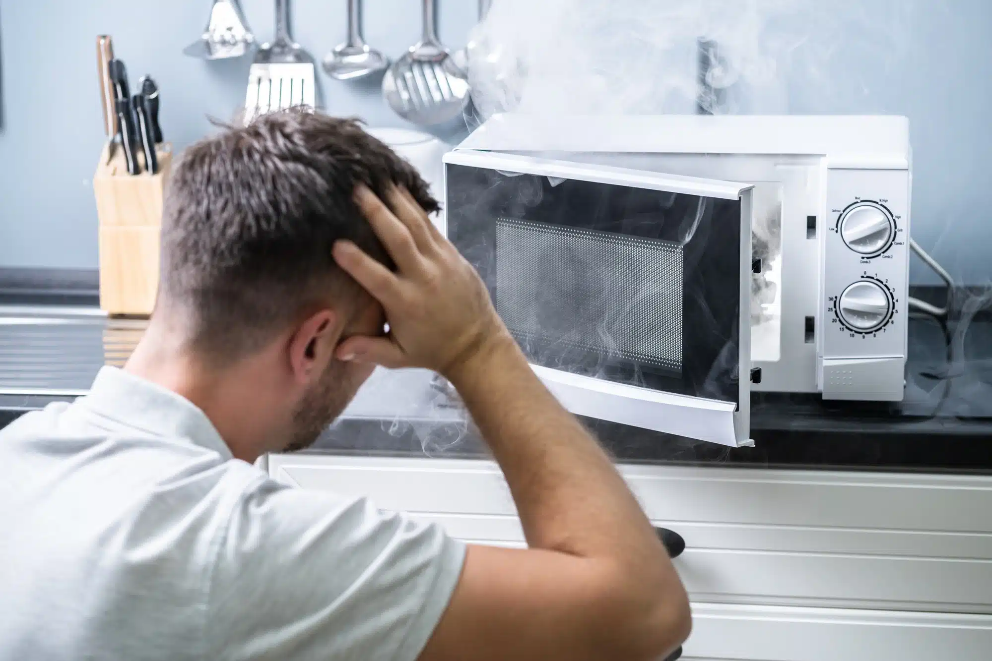 man looking at smoking microwave