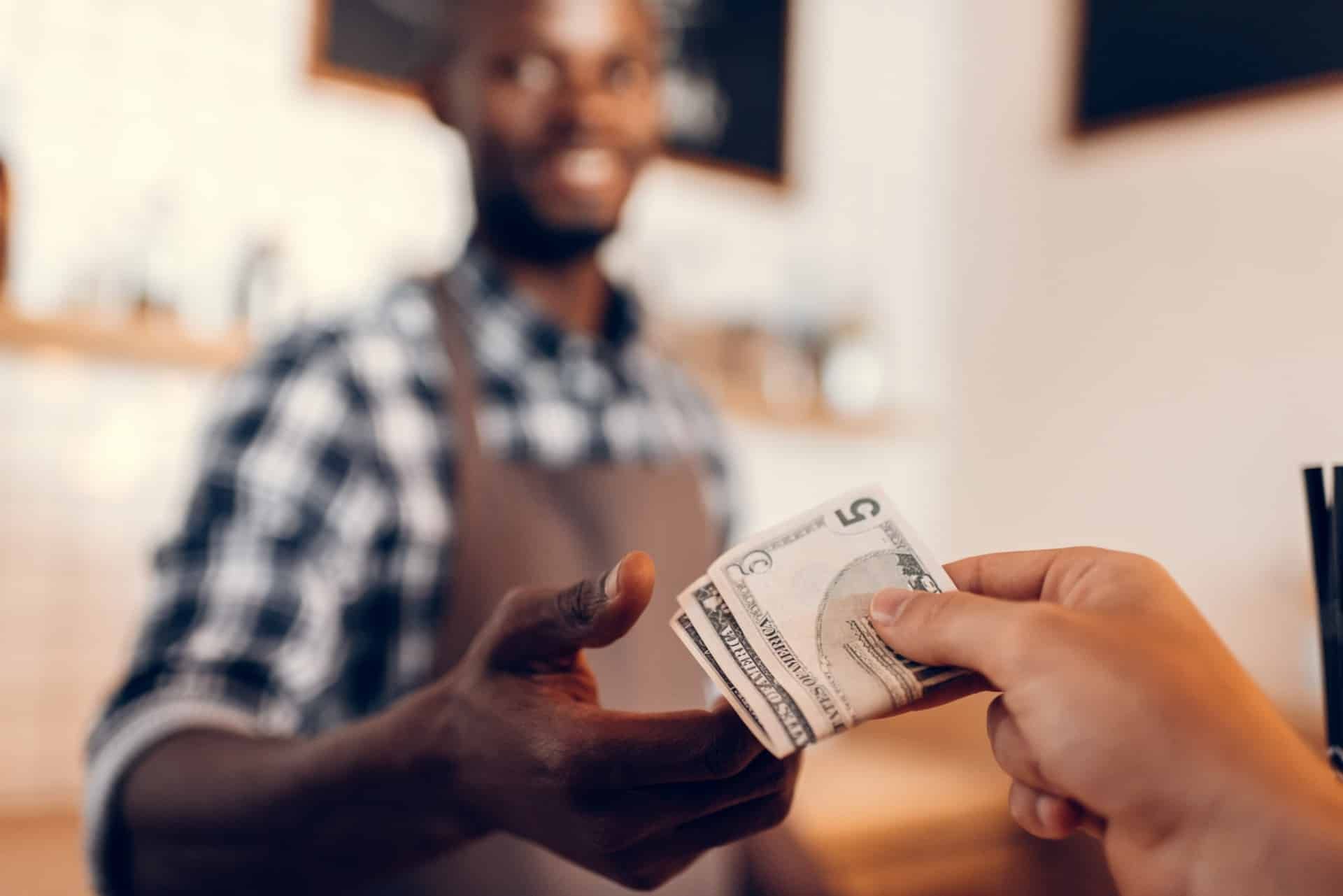 A person working at a register takes cash from a customer - chipotle customers