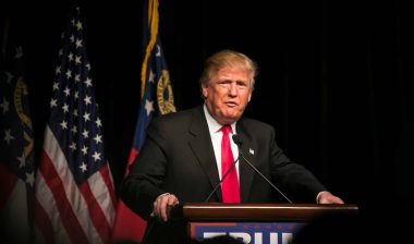 President Donald Trump stands at a podium in front of flags - executive order