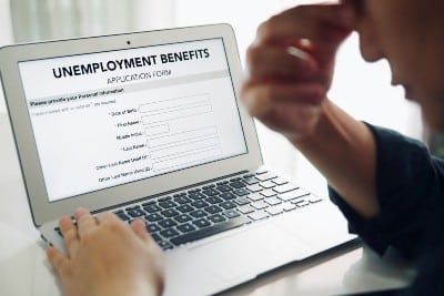 Frustrated man fills out online unemployment form on laptop - high school students