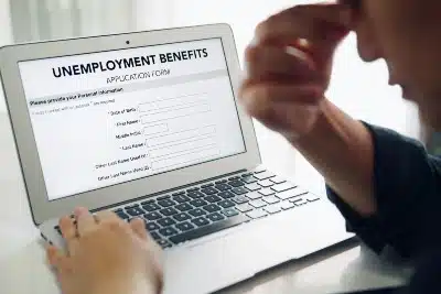 Frustrated man fills out online unemployment form on laptop - high school students