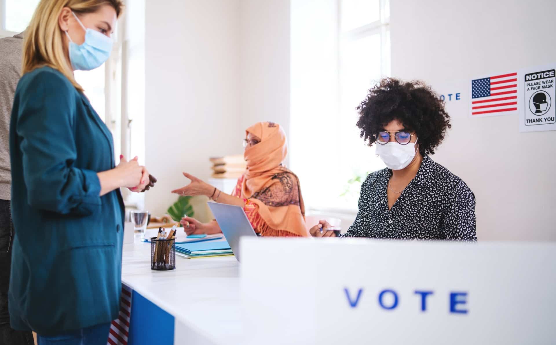 Voters speak to poll workers behind a table before voting - election day