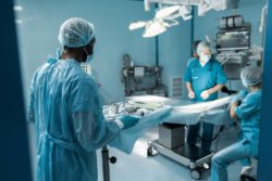 Male doctor walks holding tray of medical instruments
