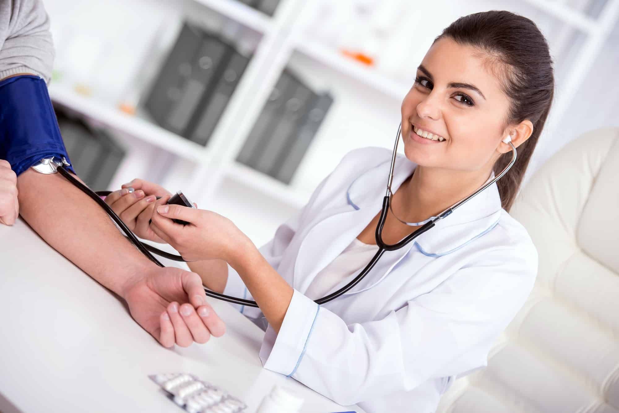 Female doctor takes patient blood pressure