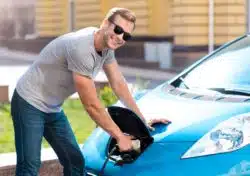 Man holds power connector to car