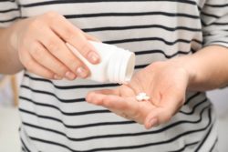 Close up of person pouring pills from bottle into hand