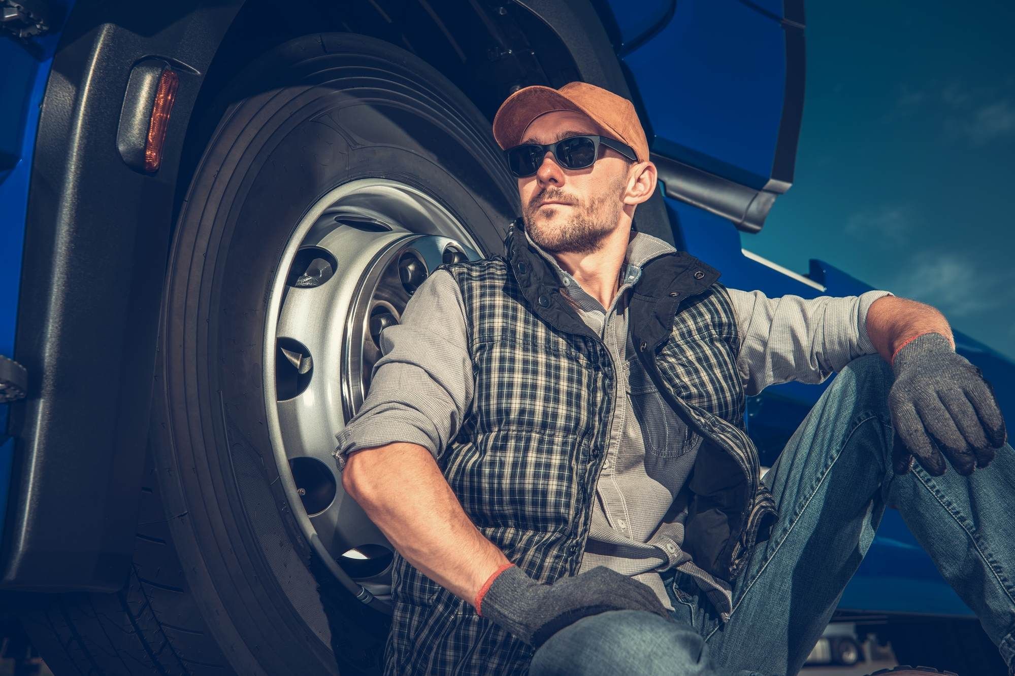 Male truck driver leans against wheel