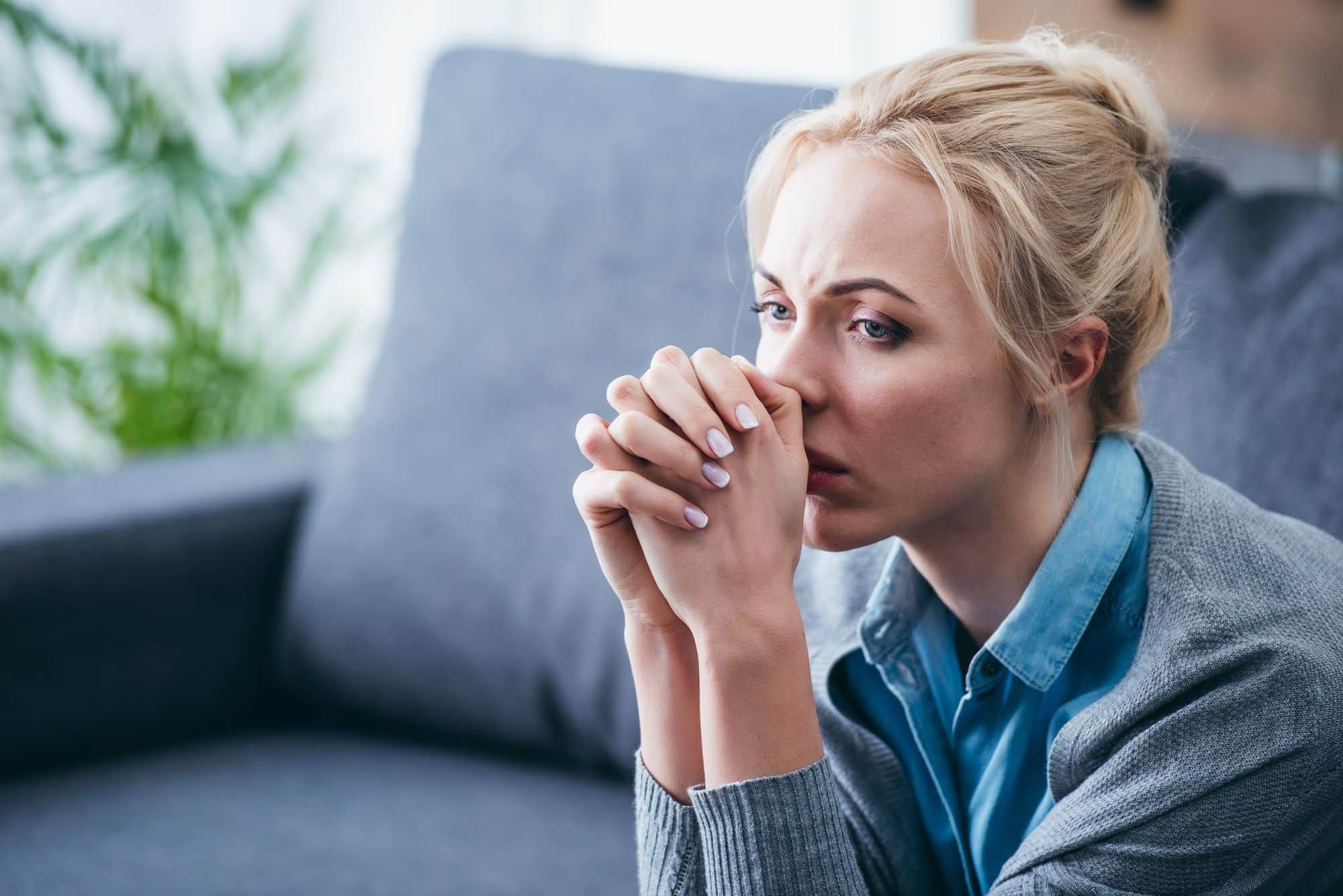 Upset woman sits on couch