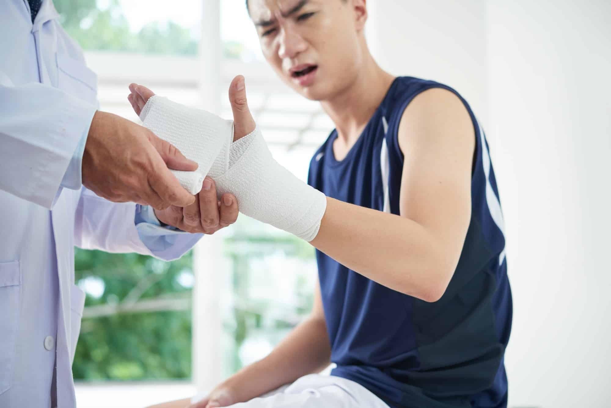 Young man gets hand and wrist bandaged by doctor