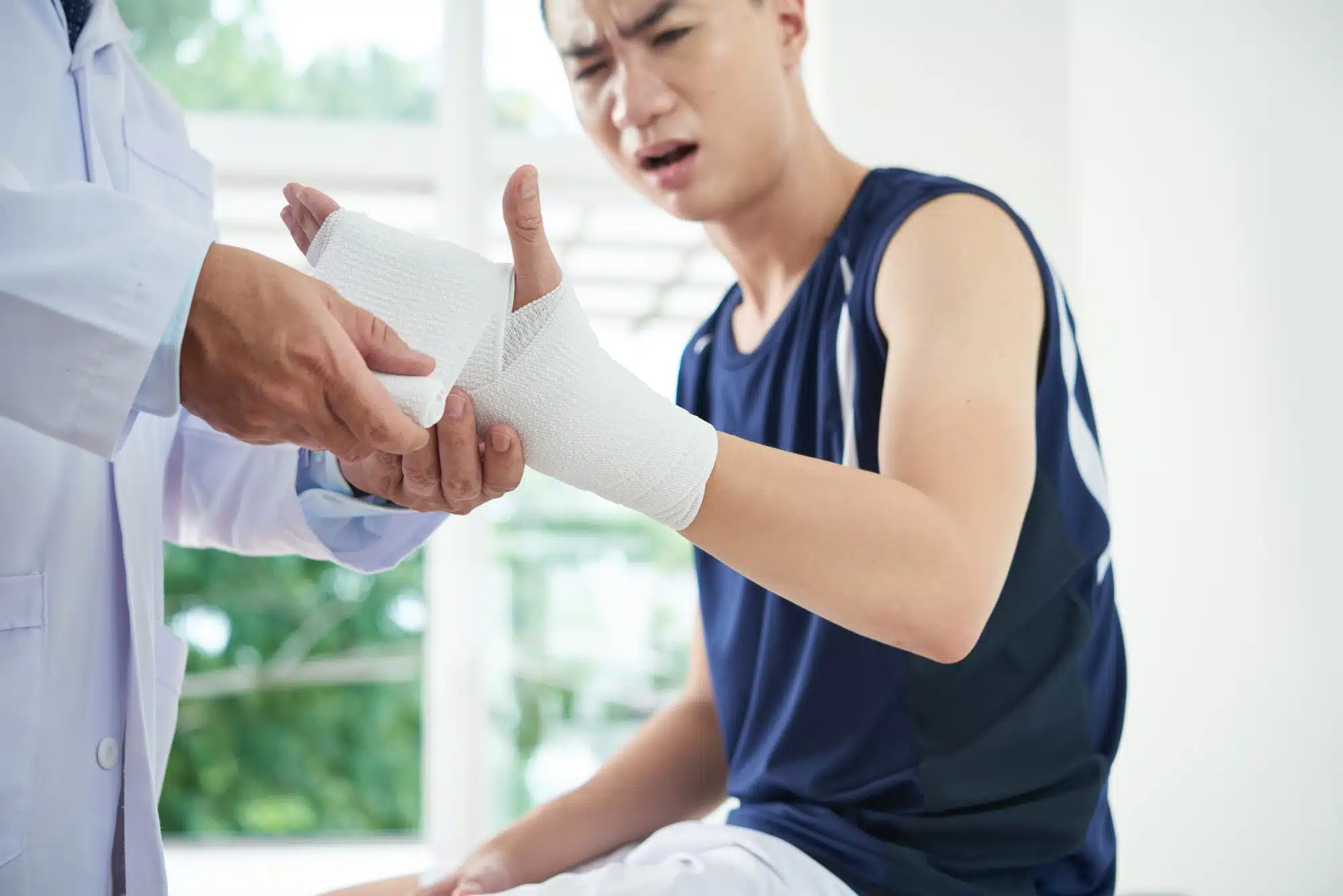 Young man gets hand and wrist bandaged by doctor