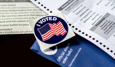 An "I voted" sticker lies near an absentee ballot and envelope - pennsylvania voters