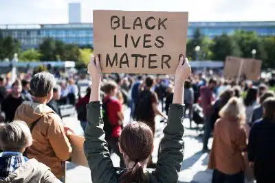People attend a protest as a woman holds up a "Black Lives Matter" sign - police brutality