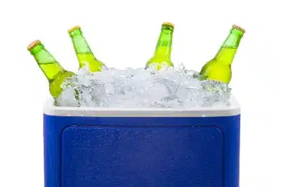 Green bottles stick up from the ice in a blue cooler - coleman ice cooler