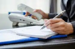 hand dialing phone and taking notes