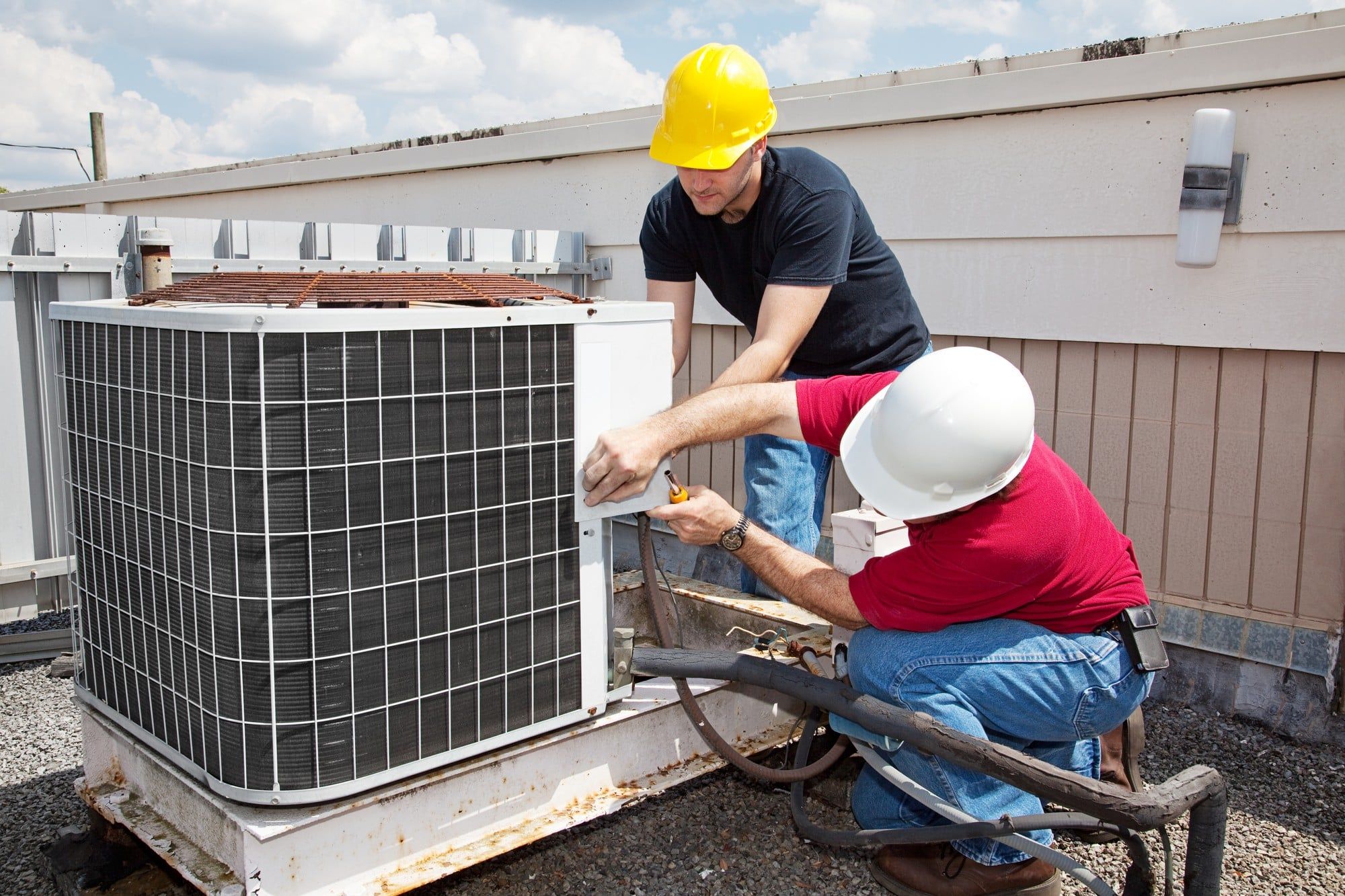 Workers repairing commercial HVAC unit