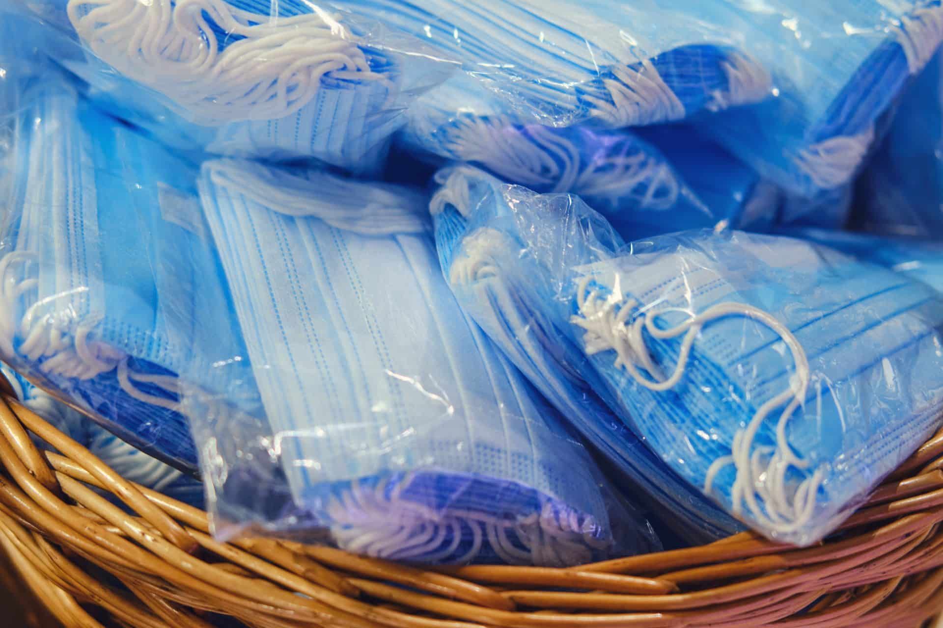 Packs of blue medical face masks lie in a brown basket - sales tax