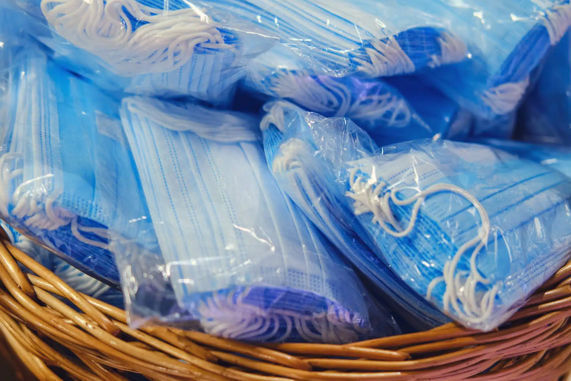 Packs of blue medical face masks lie in a brown basket - sales tax