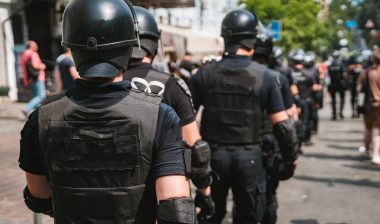 Police, seen from behind, wear riot gear to work during a protest - racial discrimination