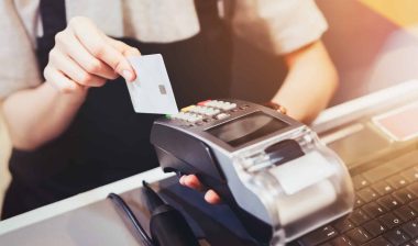 A person in an apron slides a credit card through a credit-card reader - data breach
