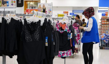 A female Walmart employee checks tags on women's clothing - walmart return policy