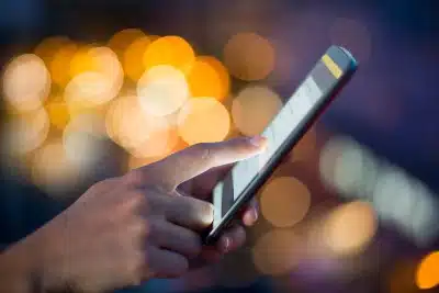 Closeup of a woman's hands using a smartphone, with lights in the background - Google tracking