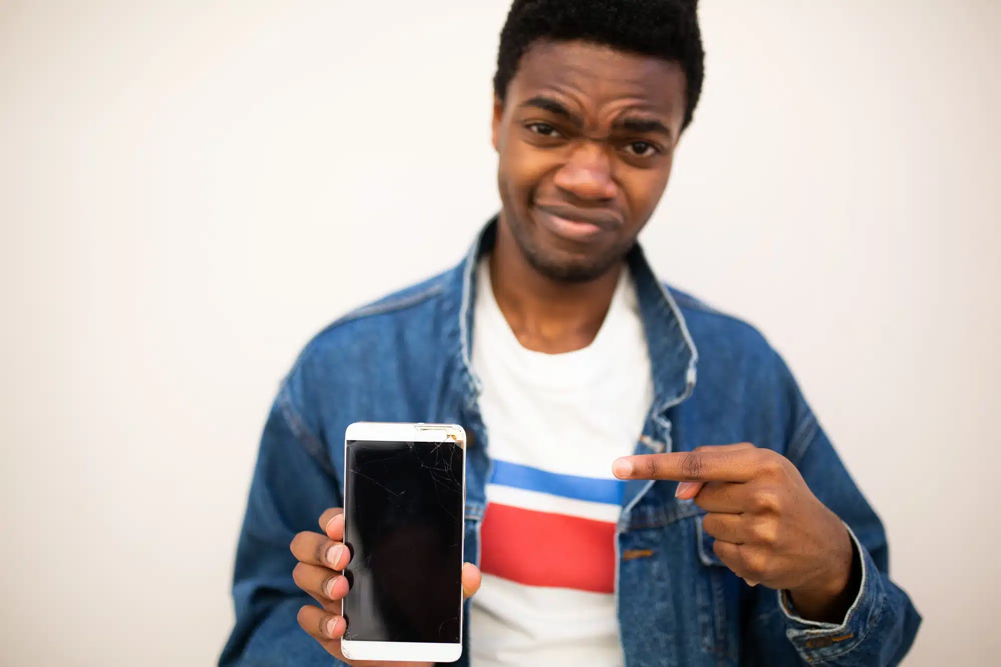 african american man holding cell ohone with annoyance