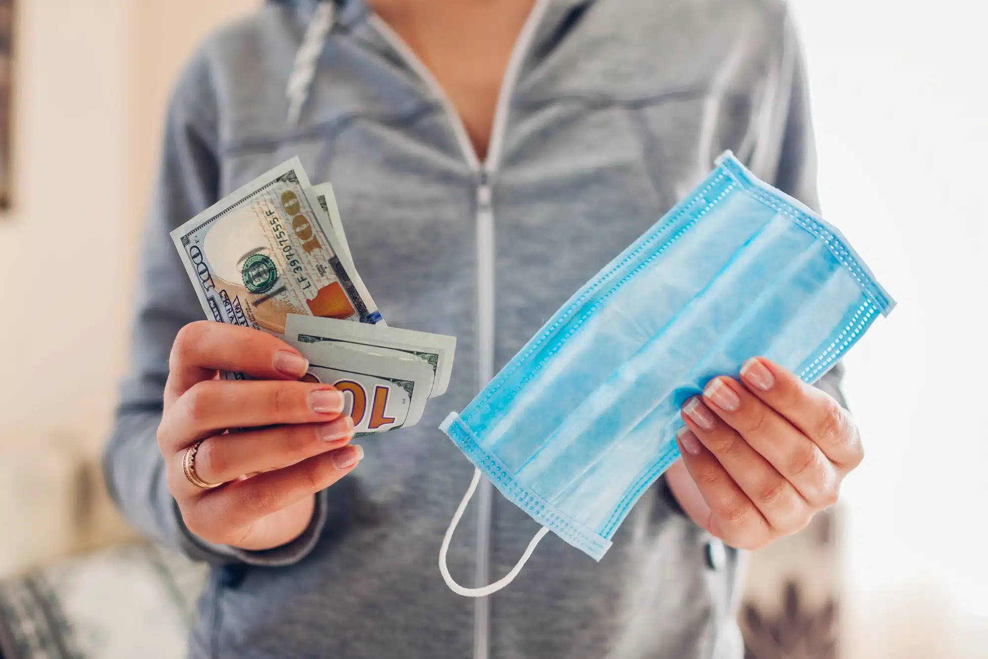 Person holding cash and mask regarding price gouging amid COVID-19