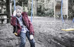 Sad boy sits on swing