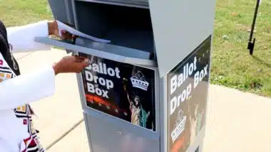 A voter drops a ballot in a drop box - Georgia voters