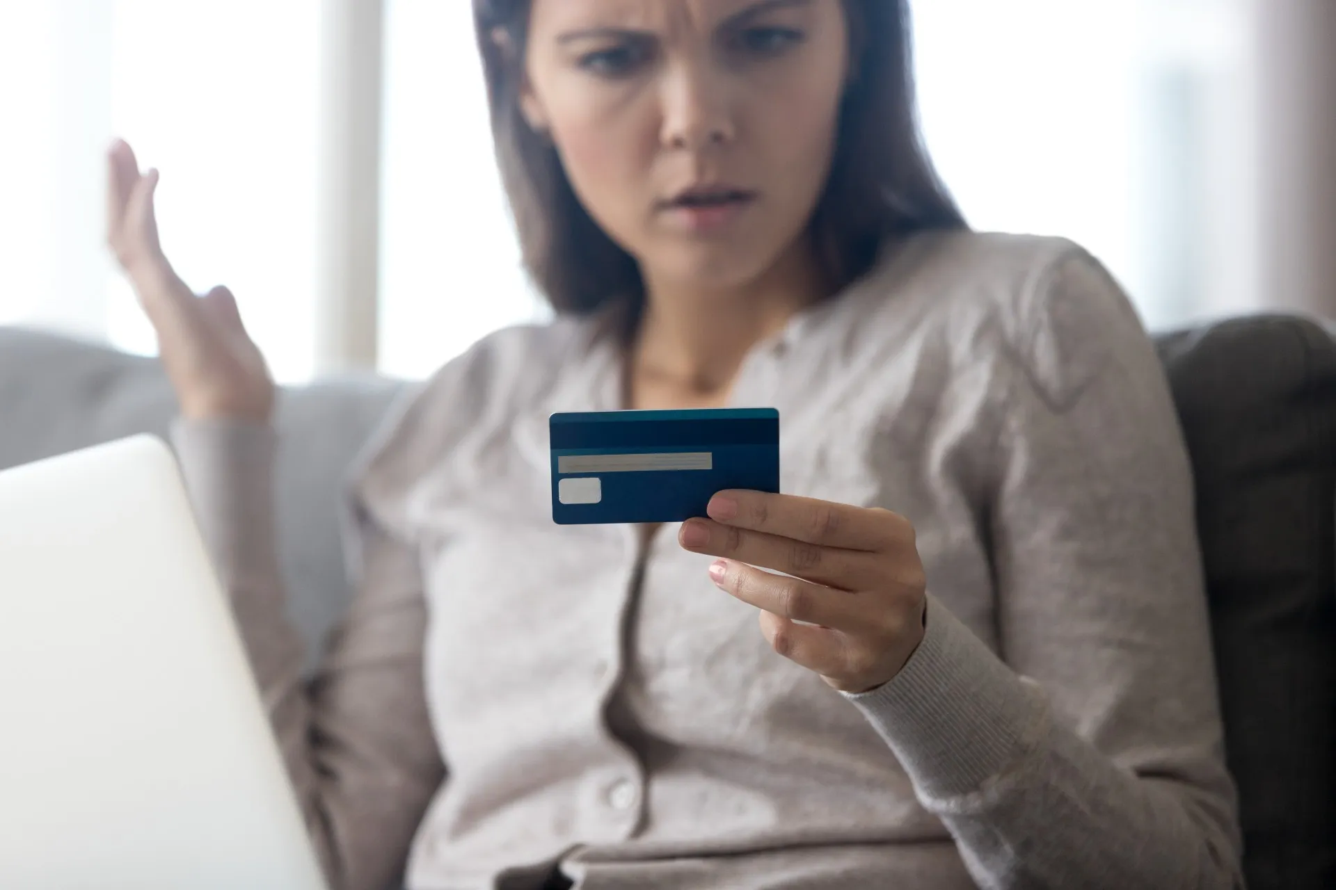 A woman looks at a credit card in annoyance - Gap rewards program