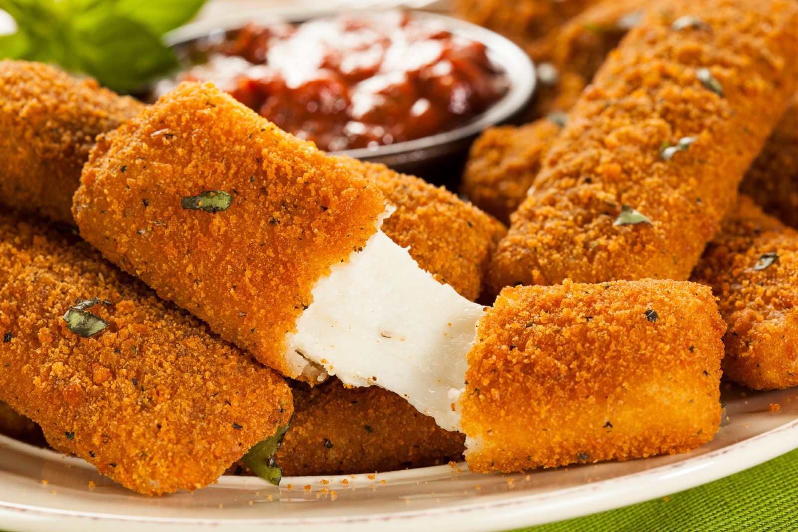 Mozzarella sticks, one broken in half, on a plate with marinara sauce - TGI Fridays Mozzarella Sticks