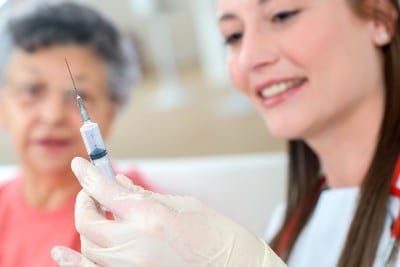A woman prepares to vaccinate an elderly woman - coronavirus vaccine