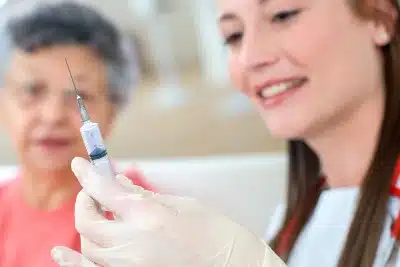 A woman prepares to vaccinate an elderly woman - coronavirus vaccine