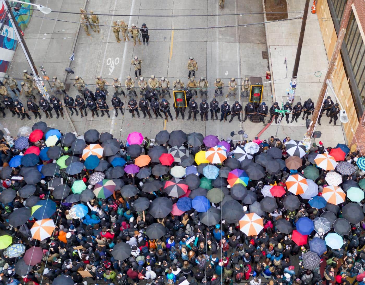 Seattle protesters stand in front of a line of police officers - police violence